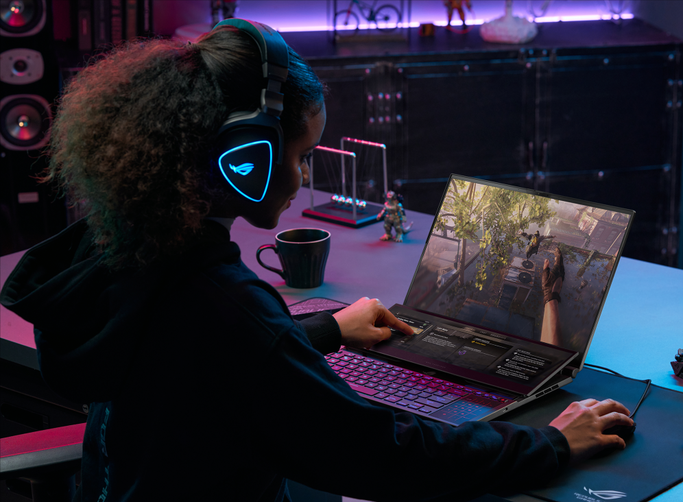 Gamer seated at a table, playing Dying Light 2 and using the touchscreen display on the Zephyrus Duo 16 with built-in game functionality.
