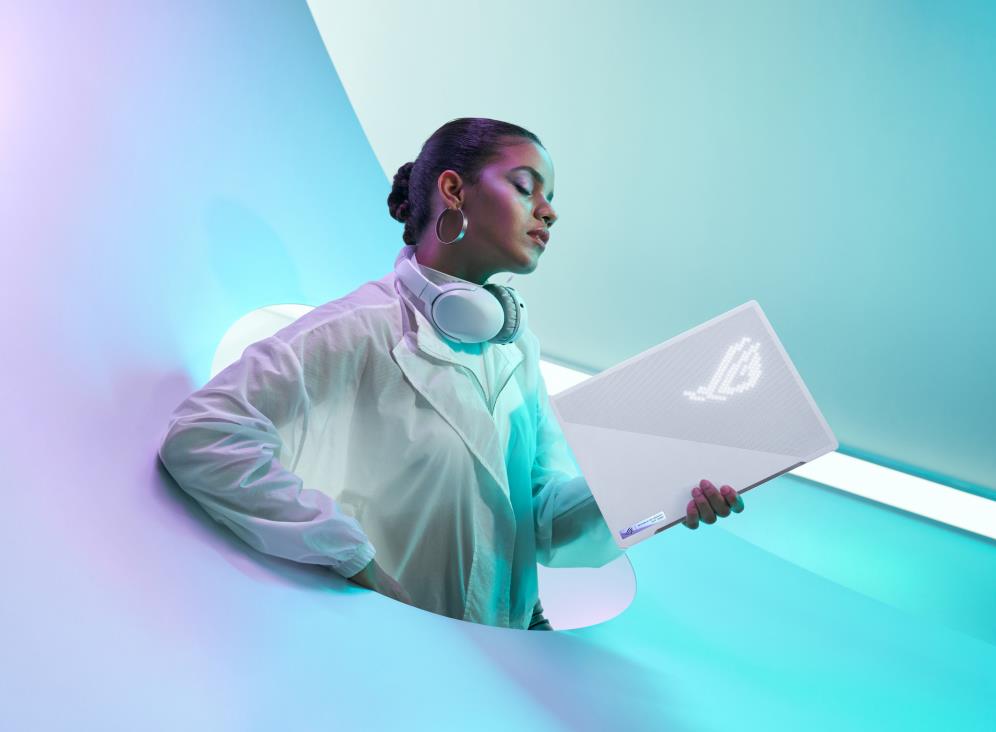 Person wearing white in an all white room, holding a white Zephyrus G14 with the ROG logo visible on the AniMe Matrix panel.