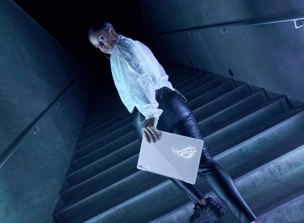 Person holding a white Zephyrus G14 on a concrete staircase, with the ROG logo on the AniMe MAtrix panel.