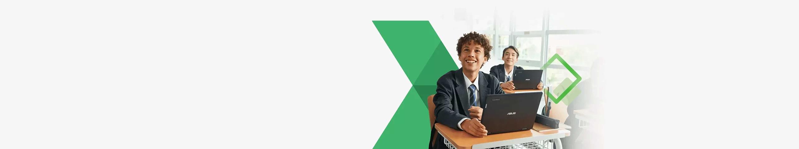 Deux élèves garçons souriant tout en ayant les ordinateurs portables Chromebook ouverts sur leurs bureaux dans la salle de classe.