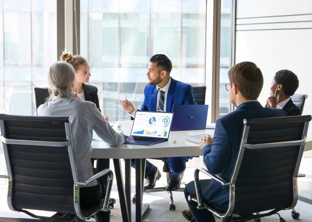 A group of employees are in a meeting room with ASUS ExpertBook laptops on the desk.